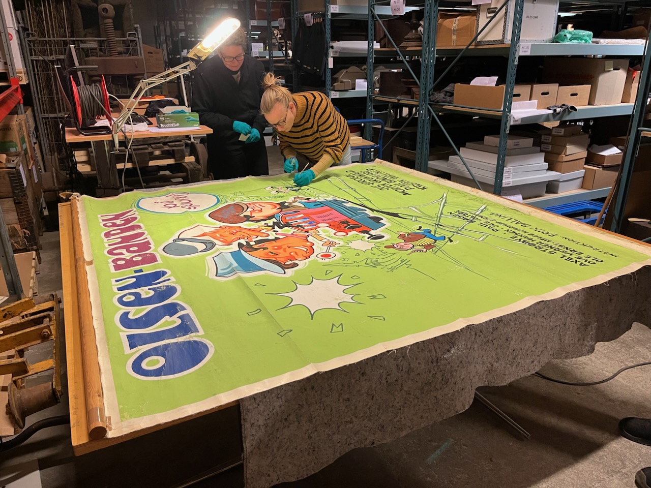 Den håndmalede premiereplakat, malet af plakatmaleren Aage Lundvald, Her i hænderne på grafisk konservator Grylle Beck Carstensen. 